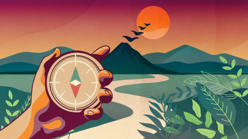 A hand holds a compass. It points north toward a winding road with a mountain and sunrise in the distance.