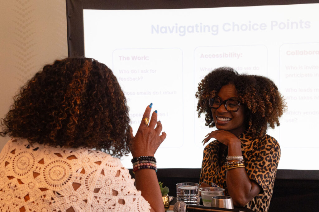Two Black women smile and talk during a small group breakout.